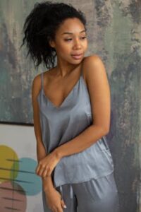 A beautiful woman poses in stylish silk pajamas against an artistic indoor backdrop.