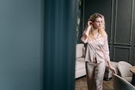 Stylish woman in satin pajamas standing in an elegant room, embodying calm and sophistication.